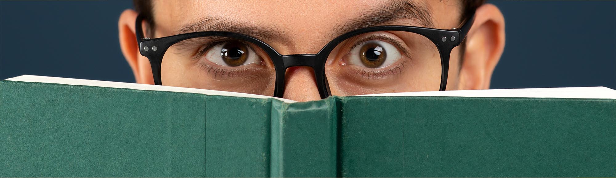 a person reading a book with an excited, wide-eyed look