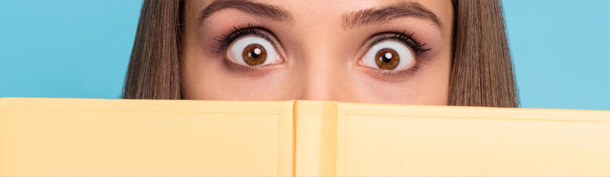 a person reading a book with an excited, wide-eyed look