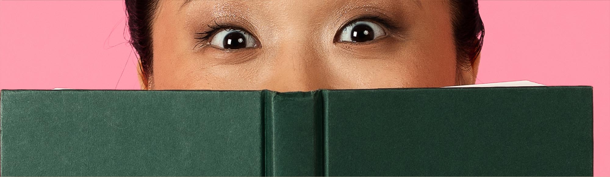 a person reading a book with an excited, wide-eyed look